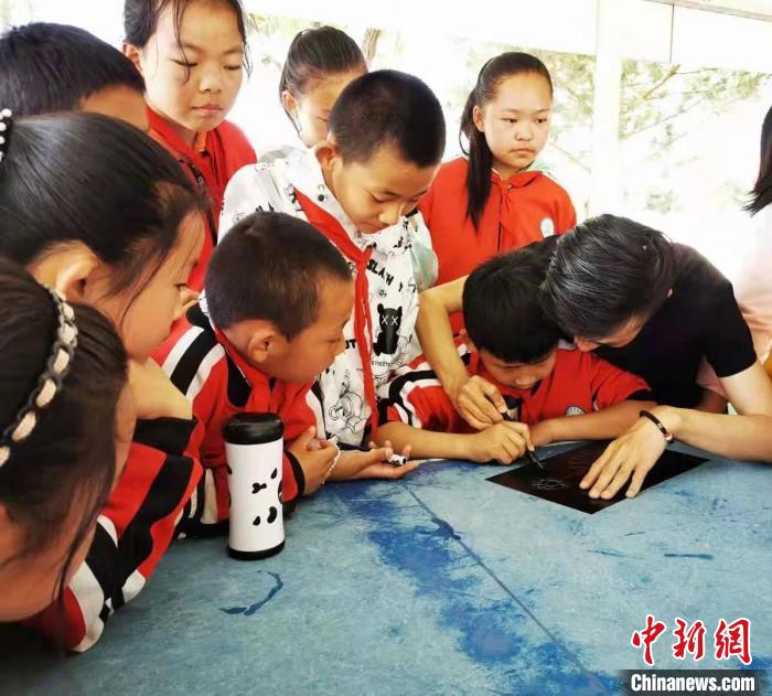 圖為朱增平(右一)教學生創作鍥金畫。(資料圖) 受訪者供圖