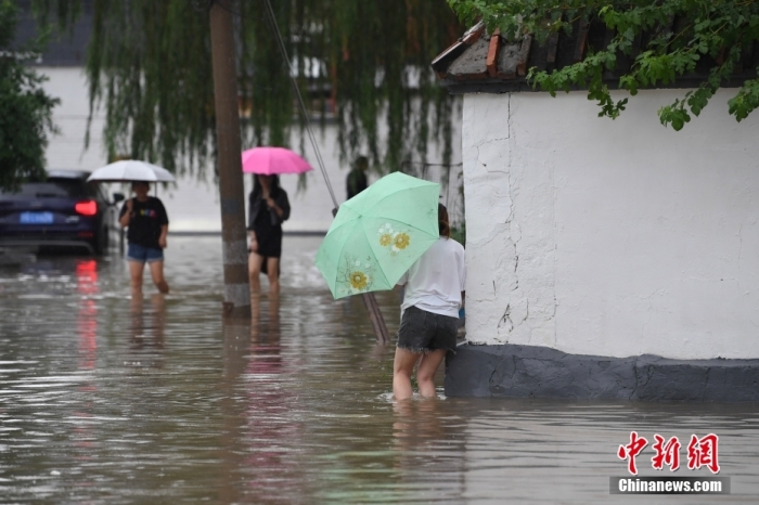 7月31日，市民行走在雨中的北京房山區(qū)瓦窯頭村。北京市氣象臺(tái)當(dāng)日10時(shí)發(fā)布分區(qū)域暴雨紅色預(yù)警信號(hào)。北京市水文總站發(fā)布洪水紅色預(yù)警，預(yù)計(jì)當(dāng)日12時(shí)至14時(shí)，房山區(qū)大石河流域?qū)⒊霈F(xiàn)紅色預(yù)警標(biāo)準(zhǔn)洪水。<a target='_blank' href='/'><p  align=