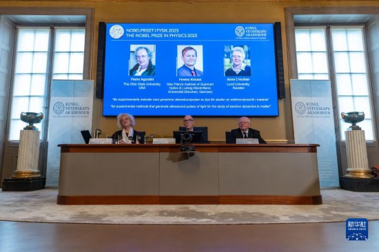 10月3日，在瑞典斯德哥爾摩舉行的2023年諾貝爾物理學獎公布現場，屏幕上顯示獎項得主皮埃爾·阿戈斯蒂尼（左）、費倫茨·克勞斯（中）和安妮·呂利耶的照片。新華社發（魏學超攝）