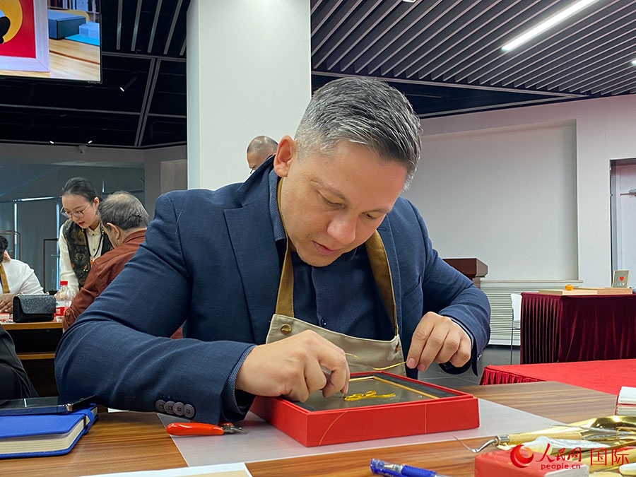 2023“一帶一路”媒體合作論壇聯合采訪團團員,親身體驗景泰藍工藝。人民網記者 于洋攝