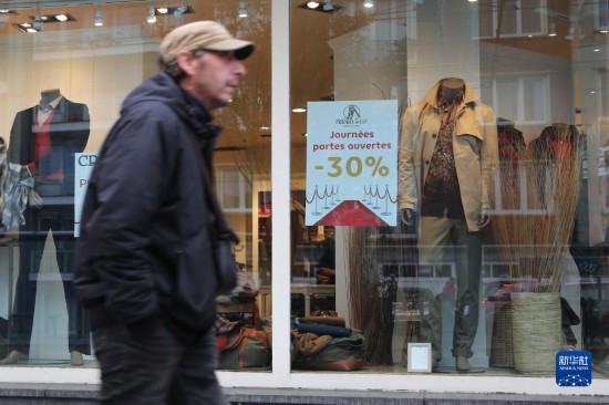10月31日,一名男子從比利時布魯塞爾一家貼有打折信息的店鋪前走過。新華社記者 趙丁喆 攝