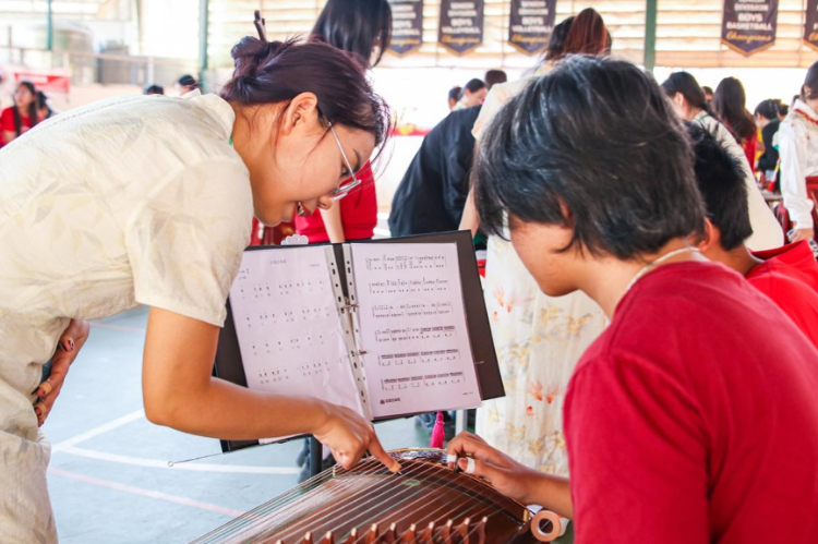 志愿者教師指導學生彈奏古箏。活動主辦方供圖