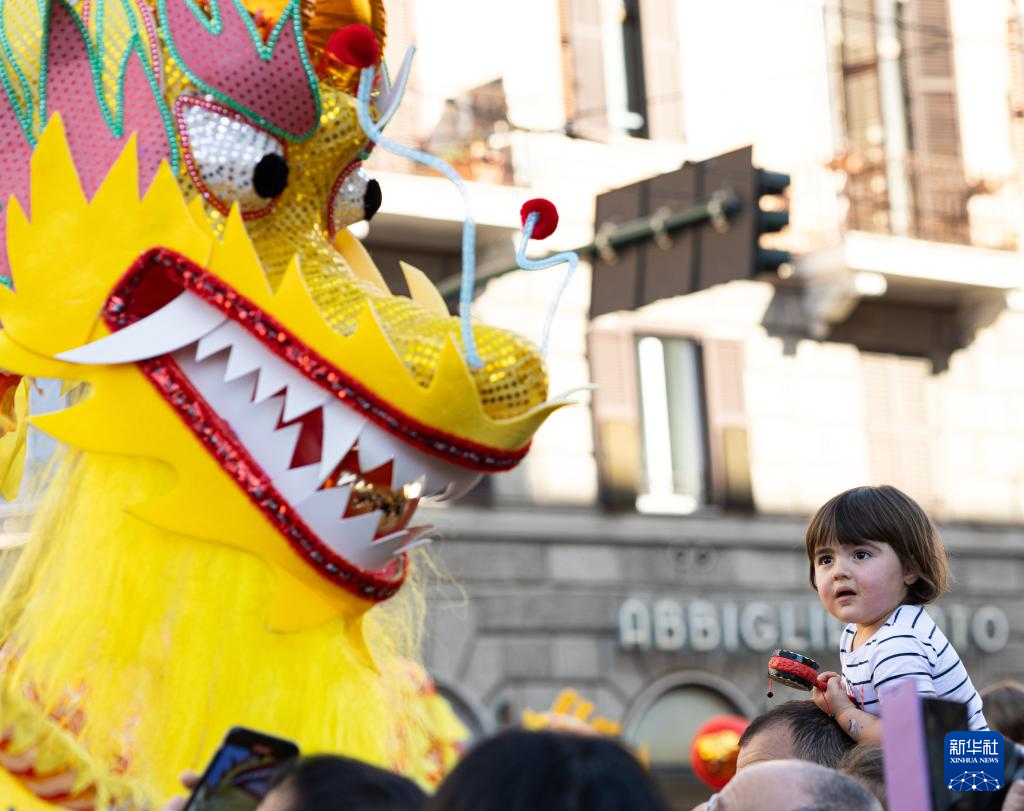 2月18日，在意大利羅馬，一名小朋友在彩妝巡游上觀看舞龍。新華社記者 李京 攝