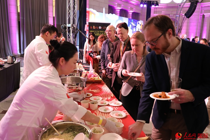 當(dāng)?shù)貢r(shí)間3月7日晚，華盛頓聯(lián)合車站廣場(chǎng)舉行駐美使團(tuán)“使館主廚挑戰(zhàn)賽”。圖為當(dāng)?shù)孛癖娫谥袊?guó)展臺(tái)前體驗(yàn)中國(guó)美食。人民網(wǎng)記者 李志偉攝