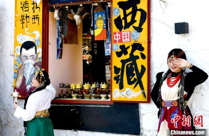 4月17日，游客身著藏式元素服裝在拉薩八廓街拍照留念。　李林 攝