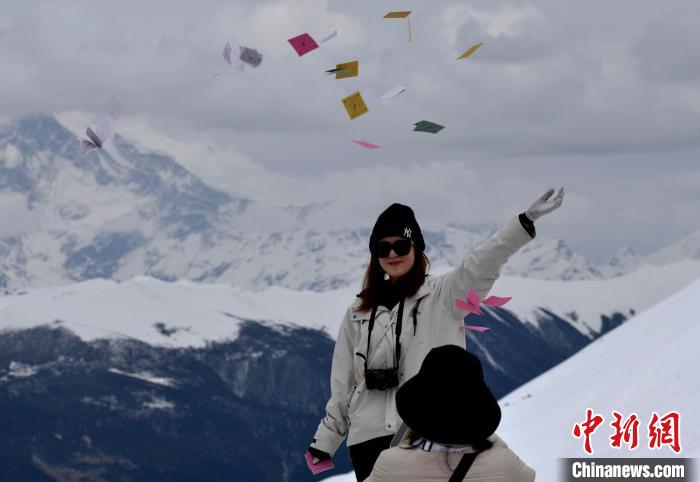 圖為5月14日，游客在西藏林芝色季拉山觀景臺拋灑“隆達”(風馬旗，藏族民眾的一種祈福方式)。　李林 攝