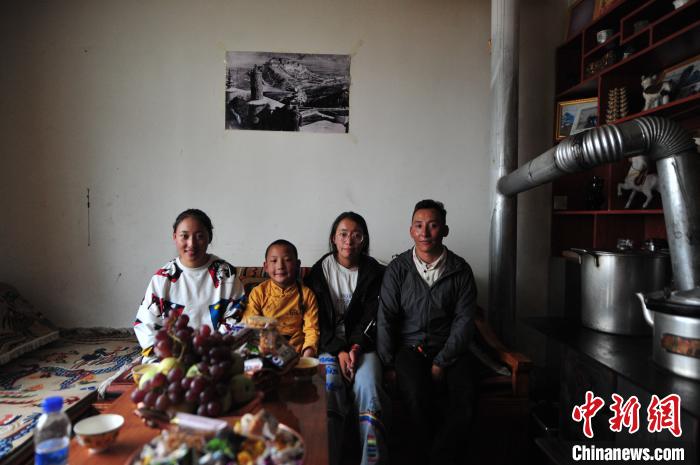 圖為8月12日，2018年7月從距那曲市色尼區(qū)城區(qū)那曲鎮(zhèn)90千米外的古露鎮(zhèn)當(dāng)桑村搬遷至城區(qū)的旦增(右一)與家人在80多平方米的新家合影(資料圖)。　張偉 攝