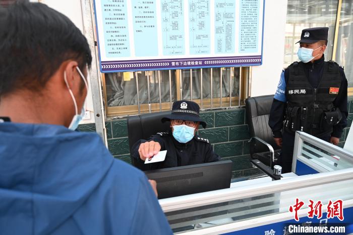 圖為移民管理警察登記完身份信息后將證件歸還給行人。 趙朗 攝