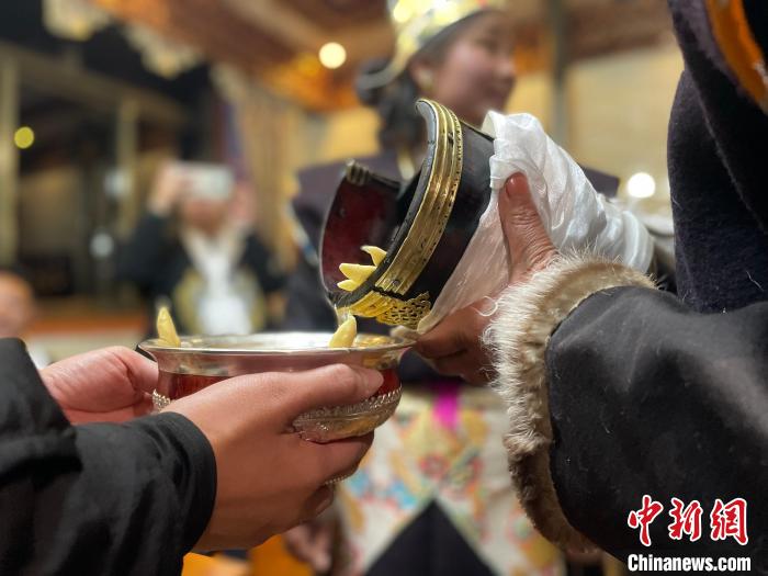 圖為主人在碗中斟滿青稞酒。 冉文娟 攝