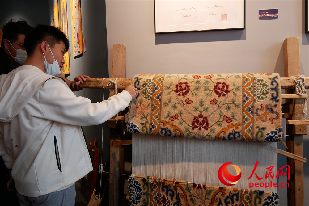 觀眾正在觀賞展出的藏毯。人民網 韋衍行攝