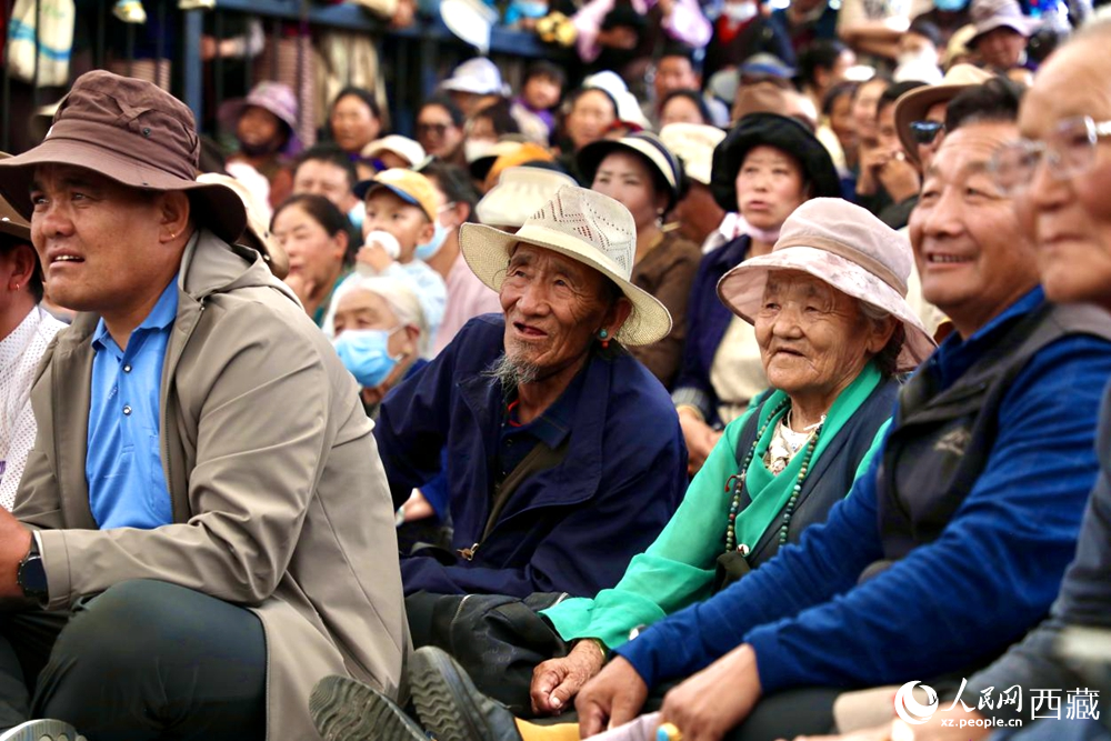 當地群眾和游客觀看藏戲演出。