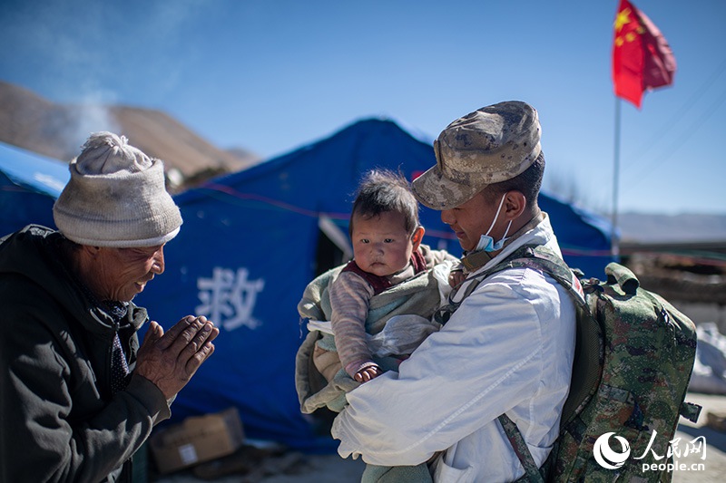 1月9日，在定日縣長所鄉(xiāng)古榮村安置點，受災群眾感謝西藏軍區(qū)陸軍某部隊衛(wèi)生員的醫(yī)療救治。人民網記者 翁奇羽攝